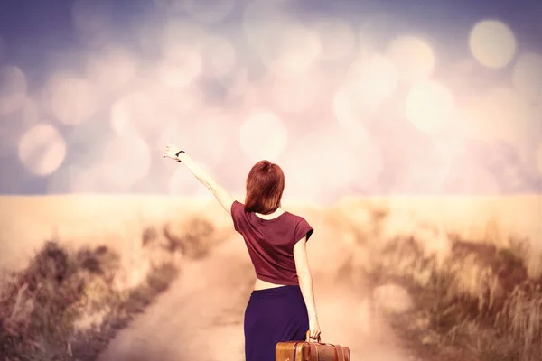 Красивая молодая женщина с чемоданом стоя — стоковое фото