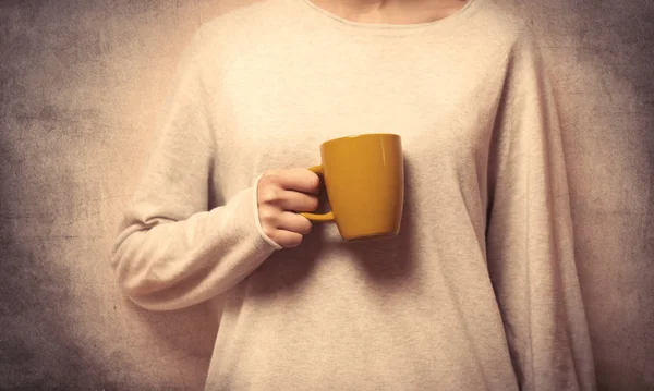 Main de femme tenant une tasse jaune — Photo