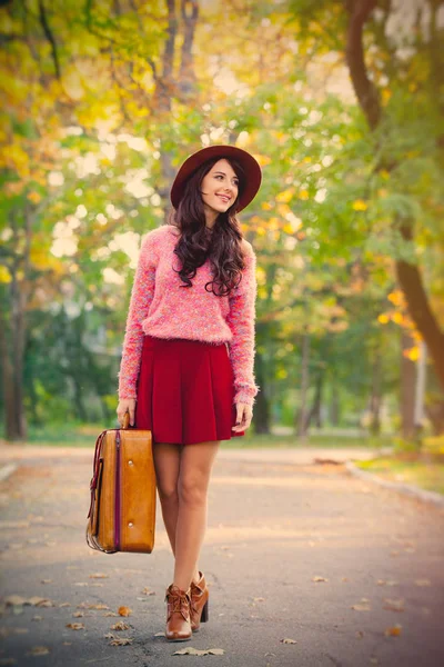 Foto de una hermosa joven con la maleta de pie a la par — Foto de Stock