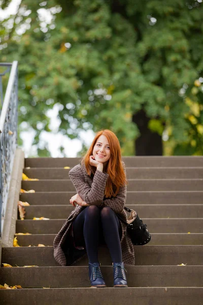 Beautiful young woman sitting on the stairs and smiling — Stock Photo, Image