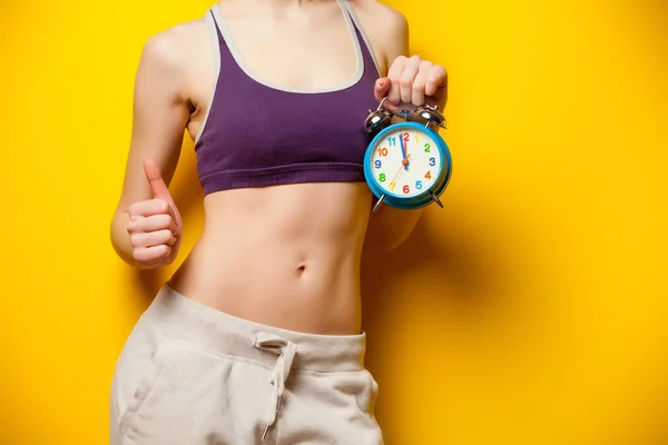 Photo of perfect slim female body with alarm clock in the hand o — Stock Photo, Image