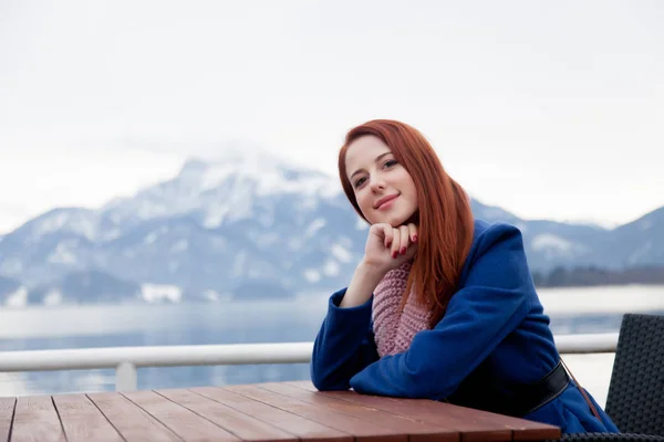 Beautiful young woman sitting near table on the mountains backgr — Stock Photo, Image
