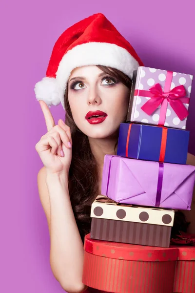 Photo of beautiful young woman with gifts in santa claus hat on — Stock Photo, Image