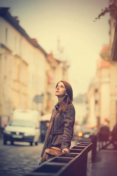 Hermosa mujer joven de pie en la calle cerca de valla y examen —  Fotos de Stock