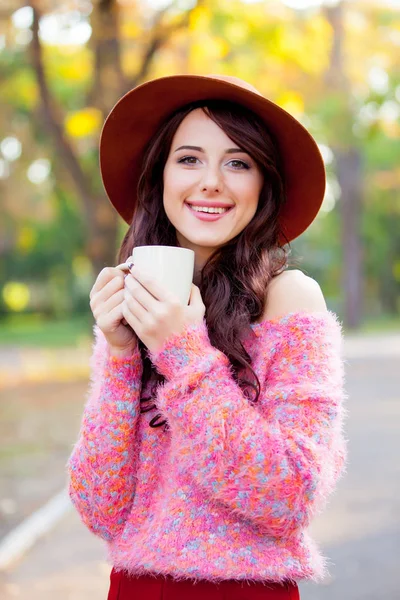 Foto van mooie jonge vrouw met kopje koffie staande in th — Stockfoto