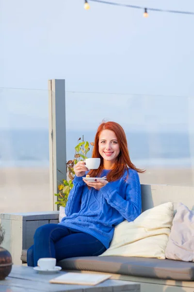 Beautiful young woman with cup of coffee sitting in the cafe on — Stock Photo, Image