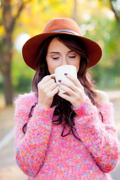 Foto de la hermosa mujer joven con taza de café de pie en th —  Fotos de Stock