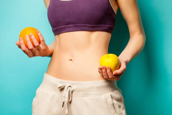 Foto de cuerpo femenino delgado perfecto con naranja y manzana en la h —  Fotos de Stock