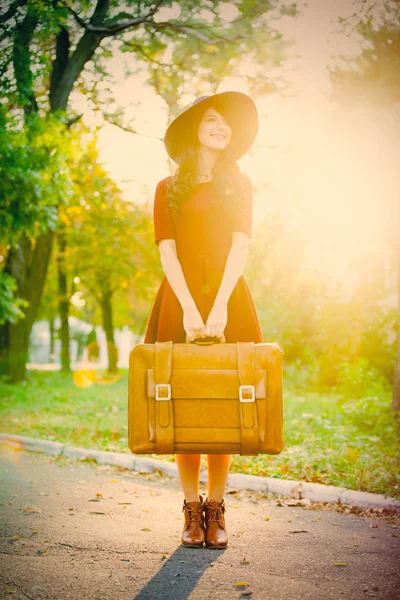 Фото красивой молодой женщины с чемоданом, стоящим в номинале — стоковое фото