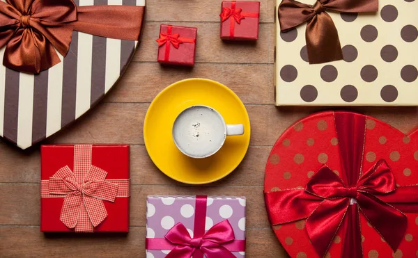Taza de café cerca de diferentes regalos de colores —  Fotos de Stock
