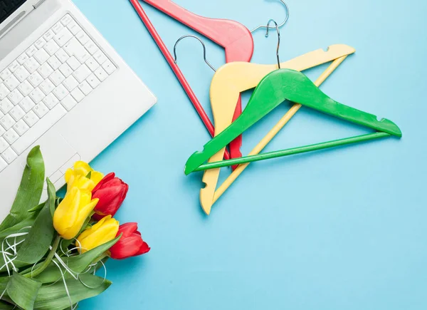 Tulips, colorful hangers and laptop — Stock Photo, Image