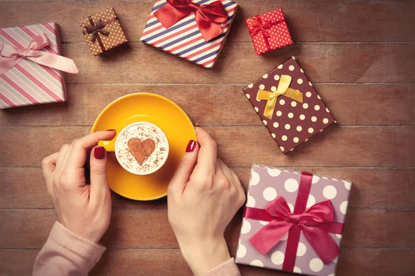 Female hands with coffee near gifts — Stock Photo, Image