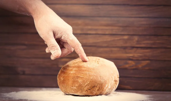 Mężczyzna ręką dotykając bochenek chleba — Zdjęcie stockowe
