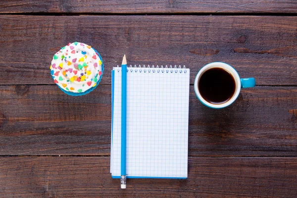 Taccuino con matita, tazza di caffè e cupcake — Foto Stock