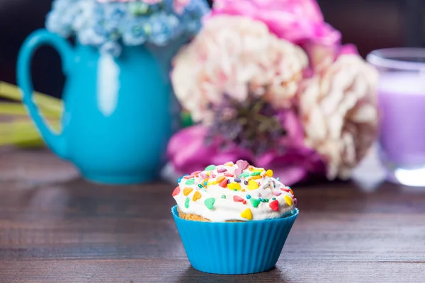 Glazed cupcake near wonderful flowers — Stock Photo, Image