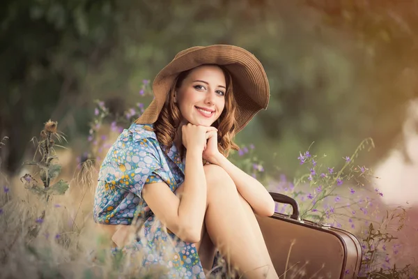 Foto av vacker ung kvinna med resväska som sitter på gras — Stockfoto