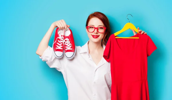 Photo of beautiful young woman holding shirt on hanger and gumsh — Stock Photo, Image
