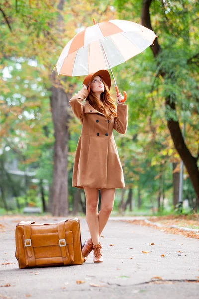 Photo of beautiful young woman standing near suitcase with umbre — Stock Photo, Image