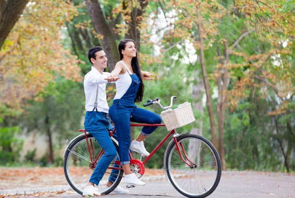 Foto de una linda pareja sentada en bicicleta y cogida de la mano en el —  Fotos de Stock