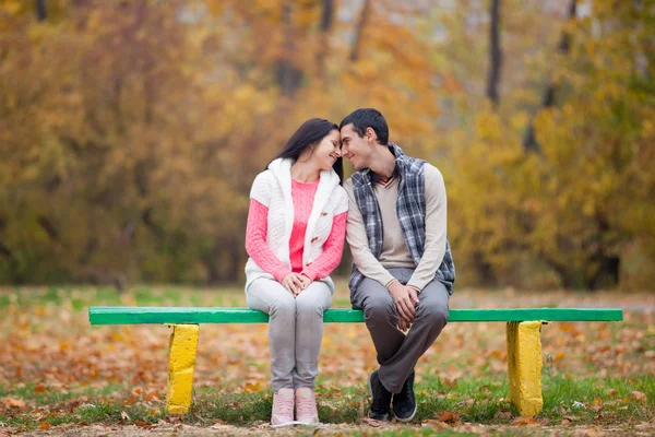 Φωτογραφία: χαριτωμένο ζευγάρι που κάθεται στον πάγκο για το εξαιρετικό autum — Φωτογραφία Αρχείου