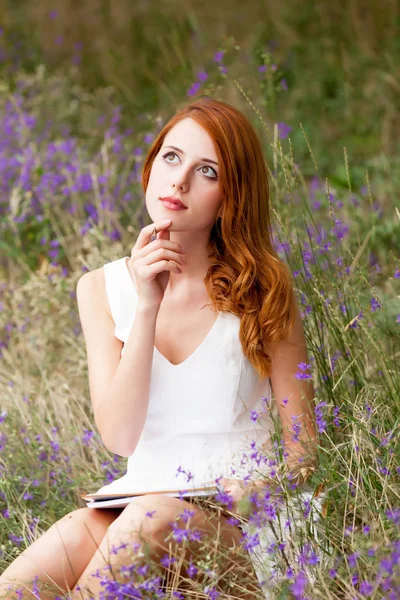Фото красивой молодой женщины с копировальной книжкой, сидящей на грас — стоковое фото