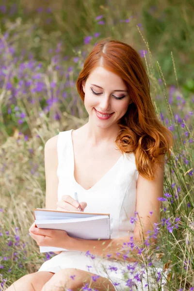 Фото красивой молодой женщины с копировальной книжкой, сидящей на грас — стоковое фото