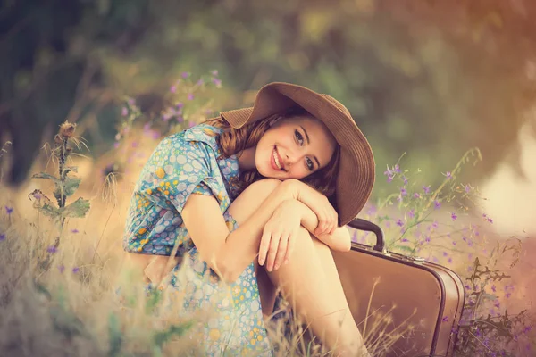 Foto di bella giovane donna con valigia seduta sul gras — Foto Stock