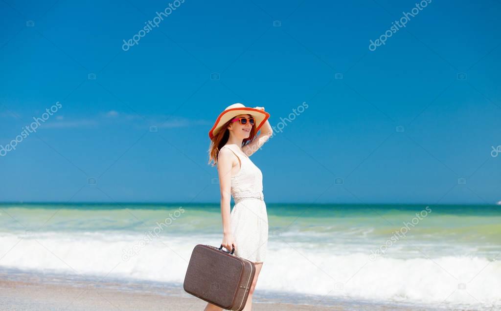 photo of beautiful young woman standing with suitcase on the won