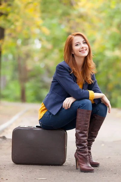 Bela jovem mulher sentada na mala — Fotografia de Stock
