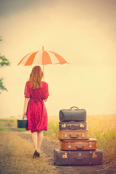 Mooie jonge vrouw met koffers en parasol — Stockfoto