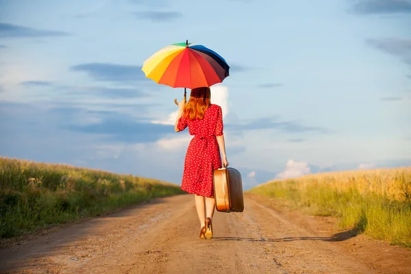 Mooie jonge vrouw met koffer en parasol — Stockfoto