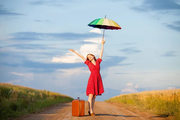 Красивая молодая женщина с чемоданом и зонтиком — стоковое фото