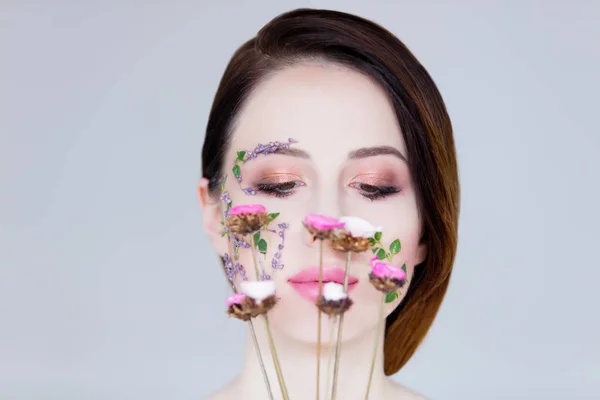 Belle jeune femme avec des fleurs sur les joues — Photo