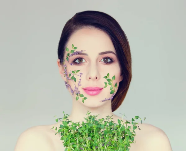 Vacker ung kvinna med blommor på kinderna — Stockfoto