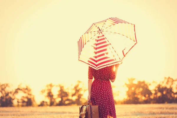 Krásná mladá žena s kufrem a deštníkem — Stock fotografie