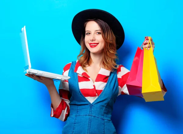 Vrouw met laptop en shopping tassen — Stockfoto