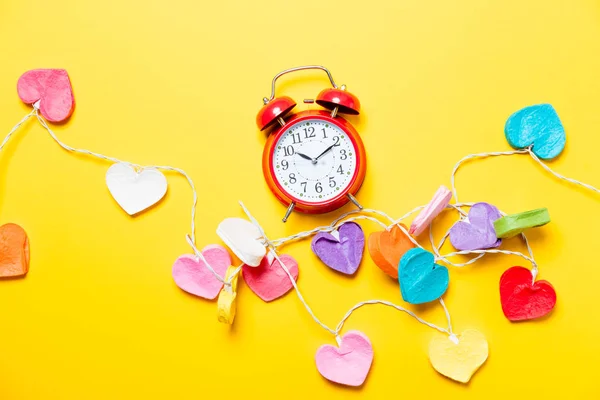 Colored heart shape lights and alarm clock — Stock Photo, Image