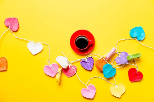 Luzes coloridas em forma de coração e xícara de café — Fotografia de Stock