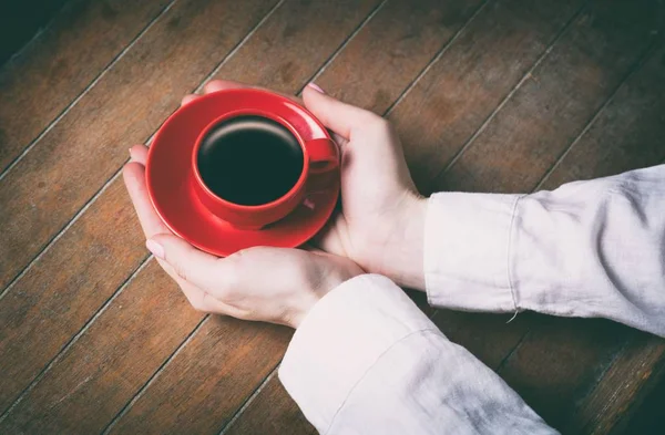 Mains de femme tenant peu de tasse de café rouge — Photo
