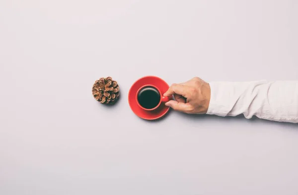 Hombre sosteniendo taza roja de café cerca de cono de pino — Foto de Stock