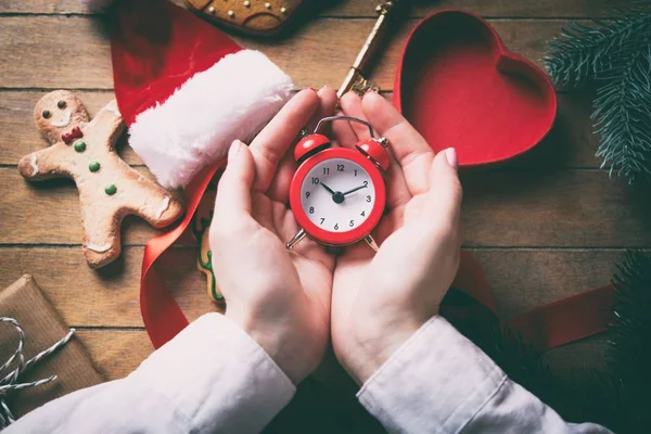 Hands wrapping christmas alarm clock and gifts — Stock Photo, Image