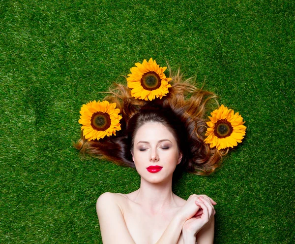 Red-haired girl with sunflowers on grass — Stock Photo, Image