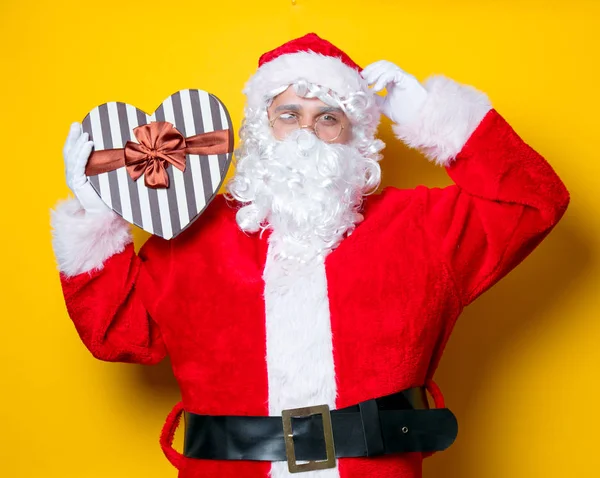 Funny Santa Claus sosteniendo el regalo en forma de corazón —  Fotos de Stock