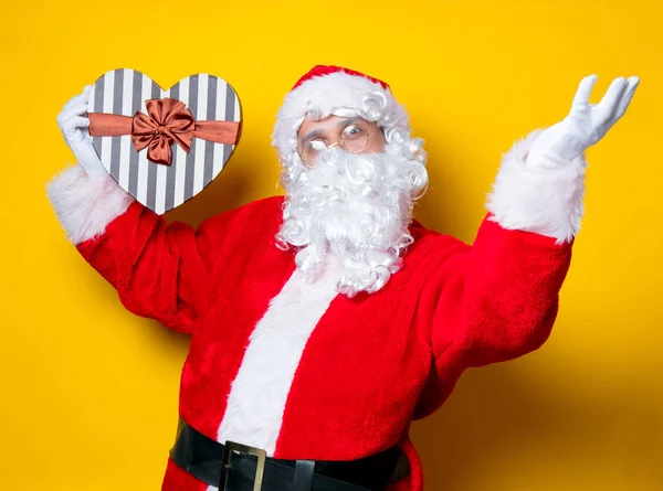 Funny Santa Claus sosteniendo el regalo en forma de corazón —  Fotos de Stock