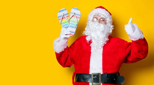 Zábavné Santa Claus drží flip flops — Stock fotografie