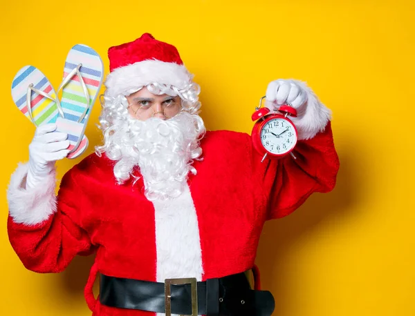 Santa Claus holding flip flops and alarm clock — Stock Photo, Image