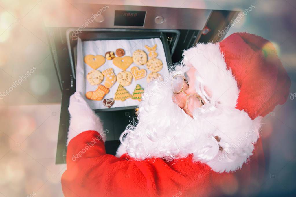 Funny Santa Claus baking a cookies in oven