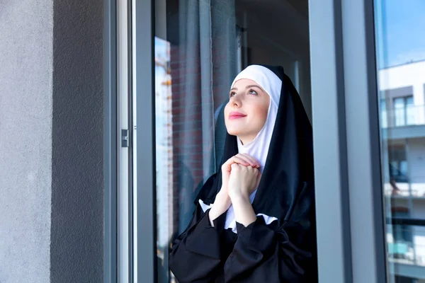 Joven monja sonriente cerca de la ventana — Foto de Stock