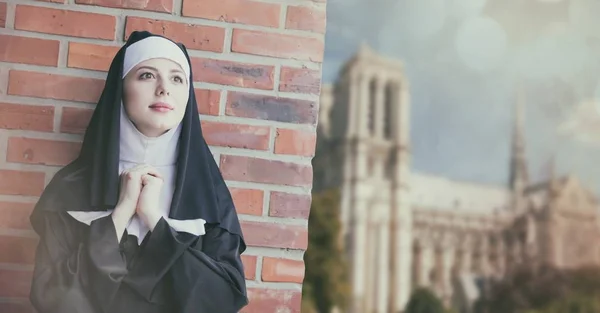 Young smiling nun standing near brick wall — Stock Photo, Image