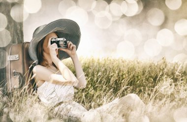 ağacın yanında fotoğraf makinesi ile oturan kadın